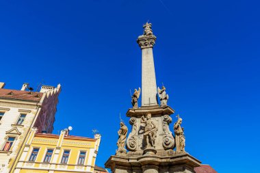 Mavi gökyüzüne karşı güneşli şehir merkezindeki heykellerin olduğu tarihi sütun. 18 Mart 2025, Madalyon, Çek Cumhuriyeti.