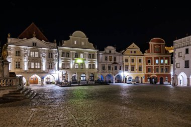 Geceleyin aydınlatılmış ortaçağ mimarisi ile tarihi kasaba meydanı. 20 Mart 2025, Cesky Krumlov, Çek.