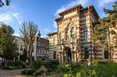 Kemerli pencereli ve manikürlü bahçeli tarihi tuğla bina. 3 Mayıs 2025 Romanya.