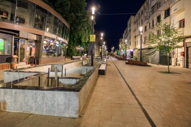 Modern binaları ve parlak ışıkları olan boş bir gece sokağı. 3 Mayıs 2025 Romanya.