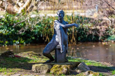 Açık hava parkında oturan bir kadının bronz heykeli. 19 Mart 2025, Karlovy Vary, Çek Cumhuriyeti.