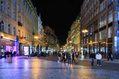 Değişik yayalarla dolu canlı şehir caddesinde gece yürüyüşü. 22 Mart 2025 Prag Çek Cumhuriyeti.