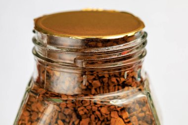 Mühürlü cam kavanoz, hafif arka planda hazır kahve tanecikleriyle dolu..