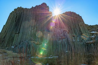 Manzaralı doğal ortamda güneş ışığı bazalt kaya sütunları üzerinde.