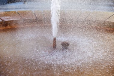 Güneş ışığıyla aydınlanan taştan zemini olan su çeşmesinin yakın görüntüsü, doğal gayzer..