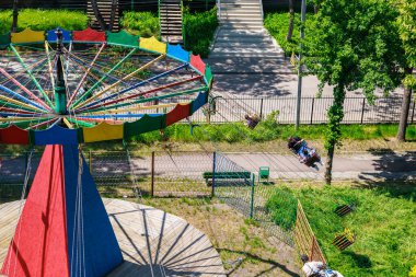 Güneşli bir günde dönen salıncaklarla lunaparkta renkli bir atlıkarınca gezisi. 22 Mayıs 2025 Balti Moldova.