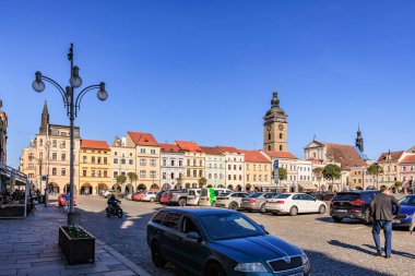 Renkli binaları ve güneşli manzaralı saat kulesi olan tarihi kasaba meydanı. 21 Mart 2025, Ceske Budejovice, Çek.