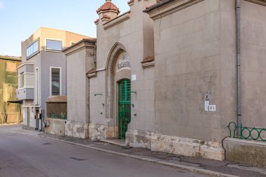 Sakin bir caddede yeşil kapısı olan eski bir taştan binanın tarihi girişi. 3 Mayıs 2025 Romanya.