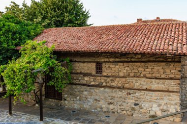 Kırmızı kiremitli ve yeşil çevresi olan geleneksel taş ev..