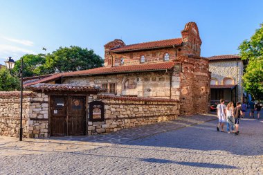 Taş duvarları ve kırmızı çatıları olan güneşli nessebar 'da tarihi kilise mimarisi. 1 Ağustos 2025, Nessebar Bulgaristan.