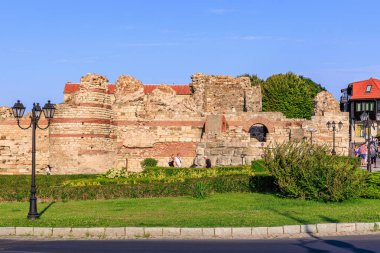 Güneşli park ortamında sokak lambaları ve bahçeli antik tuğla kalıntıları. 1 Ağustos 2025, Nessebar Bulgaristan.