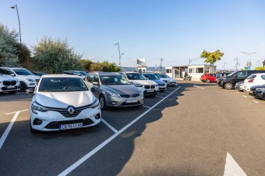 Açık mavi gökyüzünün altında asfalt yolda arabaları olan açık hava otoparkı. 1 Ağustos 2025, Nessebar Bulgaristan.
