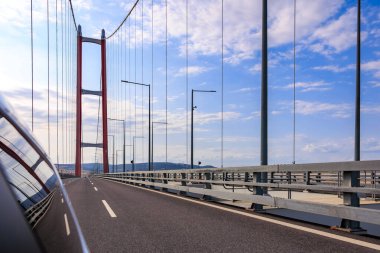 Boş yollu büyük asma köprü ve araba camında mavi gökyüzü yansımaları. 2 Ağustos 2025, Canakkale Türkiye.