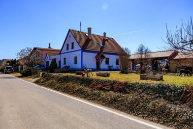 Güneşli bir günde köpeklerle güzel bir kır evi. 21 Mart 2025, Holasovice, Çek.