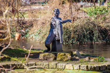 Gölün yanındaki huzur parkında bronz kadın heykeli. 19 Mart 2025, Karlovy Vary, Çek Cumhuriyeti.