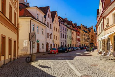 Güneşli bir günde renkli tarihi Avrupa binaları olan pitoresk bir kaldırım taşı caddesi. 18 Mart 2025, Madalyon, Çek Cumhuriyeti.