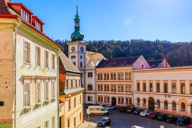 Güneşli bir günde tarihi şehir meydanında saat kulesi ve etrafındaki binalar. 18 Mart 2025, Madalyon, Çek Cumhuriyeti.