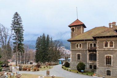 Saat kulesi olan büyük bir bina, Cantacuzino Kalesi. 15 Aralık 2024 Busteni Romanya.