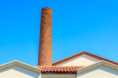 Akdeniz tarzı çatıda açık mavi gökyüzüne karşı kırmızı tuğla baca.