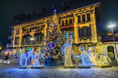 İsa gibi giyinmiş bir adam ve üç bilge adam gibi giyinmiş iki adamla bir Noel ağacı. 13 Aralık 2024 Brasov Romanya