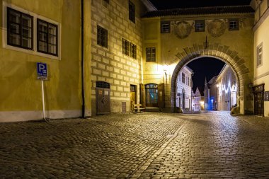 Geceleyin Avrupa 'nın tarihi kemer yolu parke taşı caddesi ve aydınlık binalarla. 20 Mart 2025, Cesky Krumlov, Çek.
