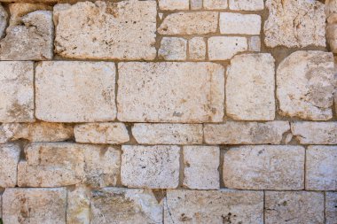 Yıpranmış kireçtaşı tuğlaları ve tarihi dokuları olan antik taş duvar. İzmir, İzmir 'de antik İzmir kalıntıları.