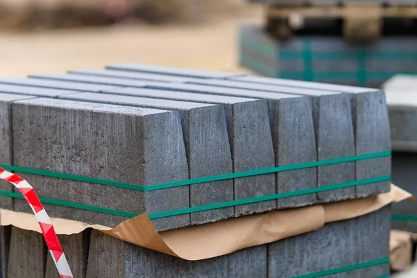 İnşaat alanında beton bloklar düzgünce istiflenmiş. Bloklar, yaklaşan inşaat projelerinde kullanılmaya hazır olduklarını gösteren yeşil kayışlarla güvenli bir şekilde sarılmış..