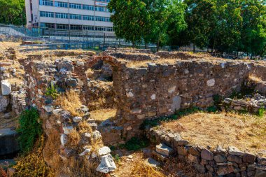 Şehir binalarının yakınlarındaki yemyeşil ağaçların arasında antik taş kalıntıları var. 4 Ağustos 2025, İzmir Türkiye.