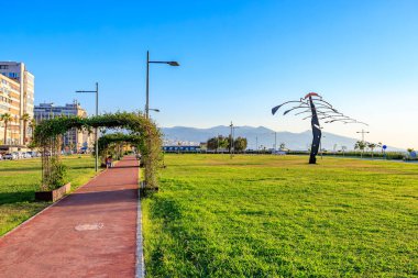 Açık bir günde yol ve heykellerle güneşli bir şehir parkı. 4 Ağustos 2025 İzmir Türkiye.