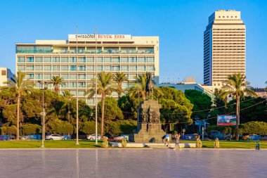 Palmiye ağaçları ve anıtı olan güneşli şehir parkı. 4 Ağustos 2025 İzmir Türkiye.