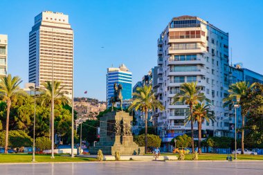 Modern mimarisi ve palmiye ağaçları olan şehir manzarasında bir heykel. 4 Ağustos 2025 İzmir Türkiye.
