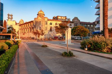 Şehir manzarasında tarihi bina ve modern sokak günbatımında. 4 Ağustos 2025 İzmir Türkiye.