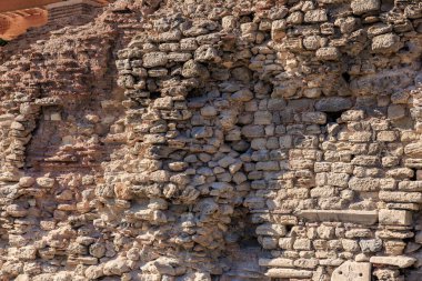 Güneş ışığında düzensiz dokusu olan antik taş bir duvar..