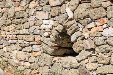 Güneşli bir günde açılan yıpranmış taş duvar.