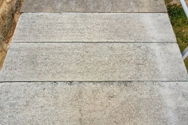 Yıpranmış beton yol, bahçedeki taş duvarlar..