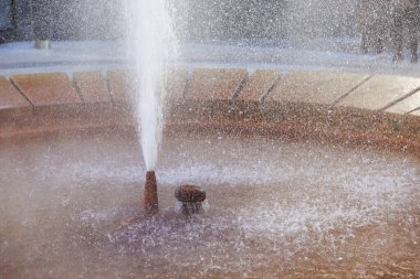 Güneşli şehir ortamında akan suyla çeşme ferahlatıcı, doğal gayzer.