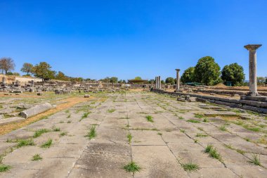 Üzerinde mavi bir gökyüzü olan büyük boş bir avlu. Avlu sütunlarla çevrili ve taş zemini var. Yunanistan 'ın antik Filippi kentinin kalıntıları