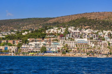 Tepe kenarındaki evleri ve berrak mavi denizi olan bir sahil kasabası. 6 Ağustos 2025, Bodrum Türkiye.