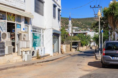 Türkiye 'nin kıyı kasabasındaki güneşli caddede market dükkanları ve arabalar görülüyor. 5 Ağustos 2025, Bodrum Türkiye.