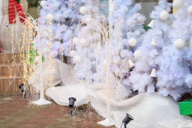 Açık hava kış sahnesinde ışıkları ve süslemeleri olan beyaz Noel ağaçları.