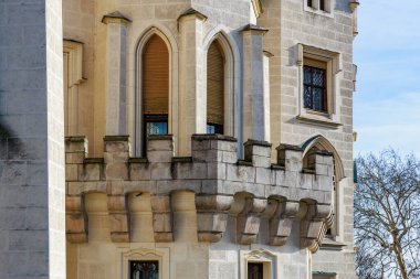 Gotik kemerli pencereleri ve payandaları olan ortaçağ taş kalesi balkonu..