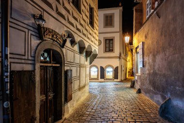 Geceleyin tarihi mimarisi ve sıcak sokak lambalarıyla muhteşem bir kaldırım taşı sokağı. 20 Mart 2025, Cesky Krumlov, Çek.