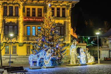 İsa gibi giyinmiş bir adamla üç figürlü bir Noel ağacı. Sahne aydınlandı ve dışarıda çekiliyor. 13 Aralık 2024 Brasov Romanya