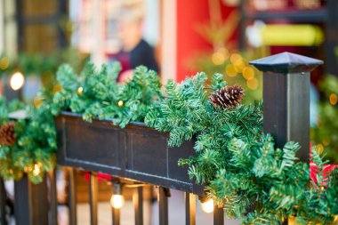 Çam kozalakları ve ışıklarla süslenmiş açık hava Noel çelengi.
