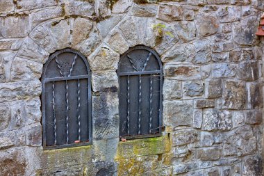 Kavisli camları ve demir parmaklıkları olan taşralı taş duvar..