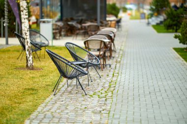 Şehir parkı düzeninde modern siyah sandalyeli ve kaldırım taşı yolu olan açık hava avlusu..