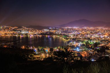 Bodrum şehrinin canlı gece manzarası ve yıldızlı gökyüzünün altında Ege kıyısı.
