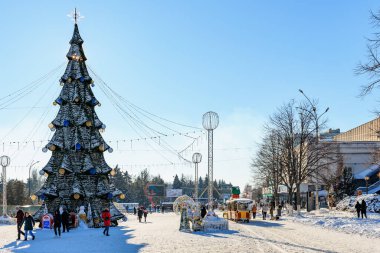 Noel ağacı ve ailelerin karlı günün tadını çıkardığı şenlikli kış harikalar diyarı. 9 Ocak 2024 Balti, Moldova.