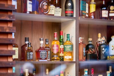 Ahşap bir dolapta raflarda sergilenen çeşitli viski ve içki şişeleri. 13 Aralık 2025 Sinaia Romanya.