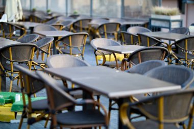 Açık kafe terasında boş rattan sandalyeler ve ahşap güvertede masalar..